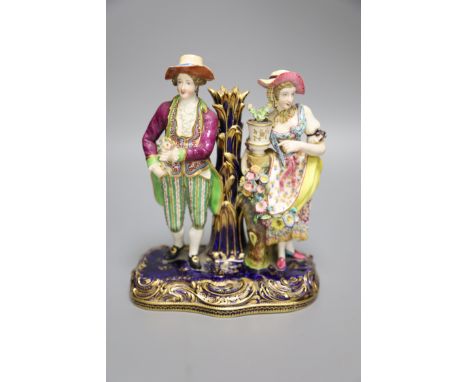 A 19th century Minton figural group and taper stick depicted as a lady and gentleman standing beside a vase of flowers, heigh