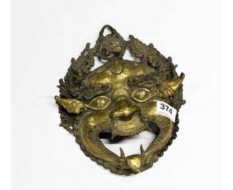 A Himalayan bronze/brass wall mounted guardian head, H. 24cm.
