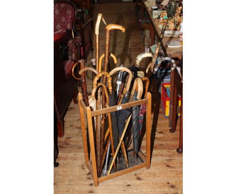 Assorted walking sticks, split cane fishing rod, brollies, shooting stick and stick stand