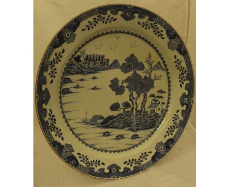 An 18th Century Chinese blue and white charger, the centre field decorated with waterside landscape with figures in boats, ra