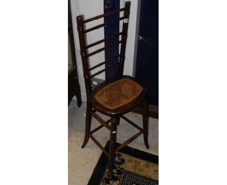 A Victorian stained beech framed and cane seated ladder back deportment chair of typical form, raised on turned and ringed ta