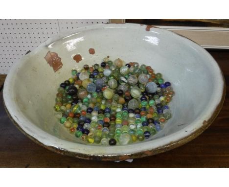 A glazed terracotta bowl containing vintage and later marbles