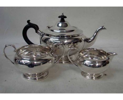 An early 20th century silver three piece Tea Service of typical compressed form comprising teapot with hinged lid, ebonised k