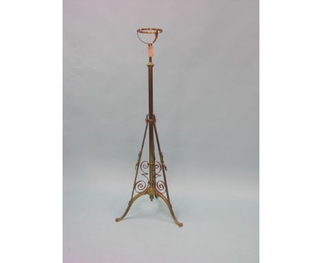 A Victorian brass floor-standing oil lamp, telescopic stem on tripod scroll base, oil fittings lacking 
