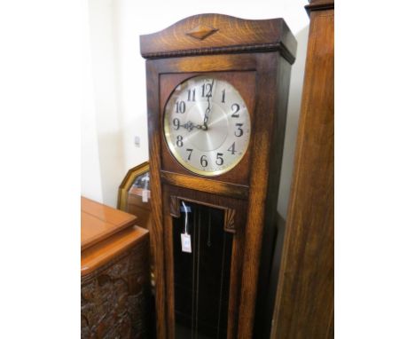 A 1930's longcase clock, with 11in. silvered dial and chiming movement, in oak case with glazed trunk door, with pendulum and