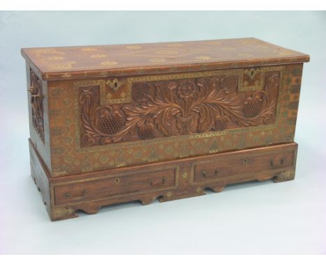 A middle-eastern rosewood-type trunk, with inlaid brass embellishments and mounts throughout, floral carved frontage and two 