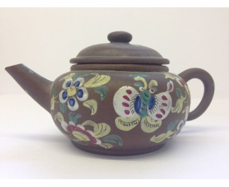 A Chinese terracotta teapot with enamel floral decoration.