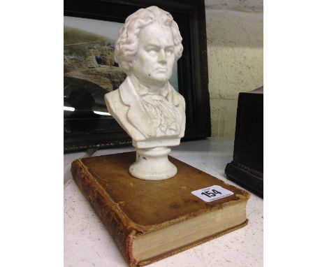 A small Bisque china bust of Beethoven together with an 18th century leather bound French book.