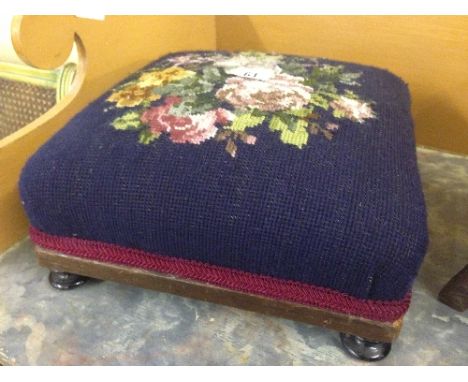 A small square tapestry upholstered footstool.