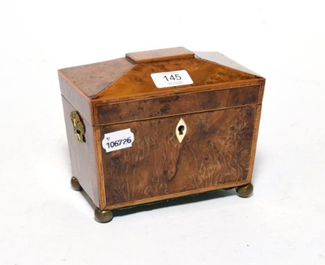 A Regency walnut tea caddy with sarcophagus top, on brass bun feet