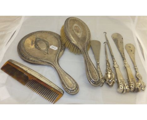 A silver backed hand mirror and matching brush, various silver handled shoe horns and button hooks and a silver mounted comb