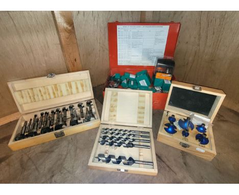 A red metal case containing a selection of carbide tipped router bits, a wooden box containing six Blue Tornado router bits, 