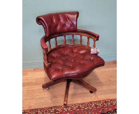 A modern swivel office chair, upholstered in burgundy button back leather, having adjustable height, raised on five out swept