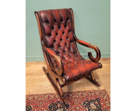 A 20th century Chesterfield style slipper rocking chair, with open armrests, having deep button oxblood leather upholstery, W