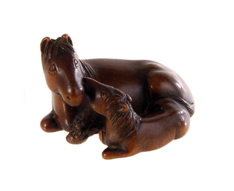 A late Meiji period Japanese carved boxwood horse group netsuke, modelled as a recumbent horse and foal, bearing signature to