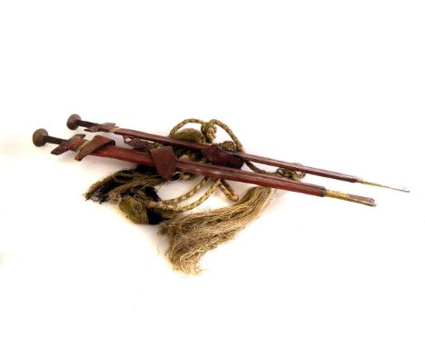 A pair of African leather scabbard swords, having gilt metal bracelets around the scabbards (4)