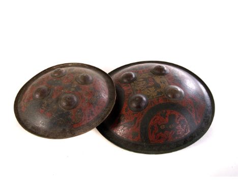 Two Indian brass and enamel shields, decorated with gold and red enamel animal and floral design, with four added raised shie