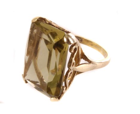 A 9ct gold and citrine dress ring, the large rectangular cut yellow stone set in four short claw mount, having pierced design