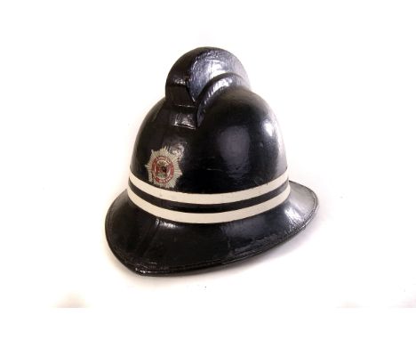 A pre-1965 Carlisle Fire Brigade helmet, the black helmet with transfer shield of Carlisle to front with two white strips run