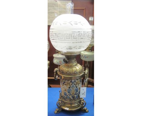 Brass double burner oil lamp, having glass reservoir within a brass mounted two handled incised and enamelled foliate design 