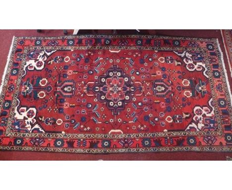 A Hamadan carpet with central floral medallion on a rouge ground contained by floral borders. 276 x 146cm 