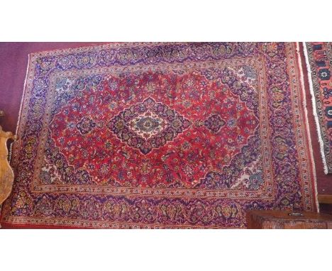 A Kashan carpet with central floral medallion on a red and blue ground contained by floral borders. 297 x 201cm 