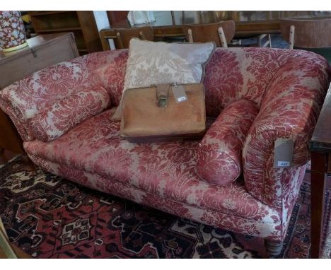 An early 20th century chesterfield sofa, with red damask upholstery, raised on turned legs and castors. 