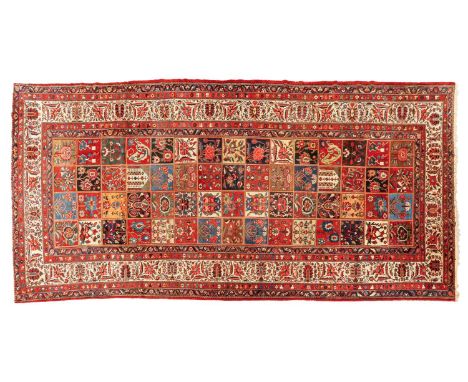 A large old Baktiari main carpet with a multi-section tiled field filled with flowers and palmettes in distinctive dark, pale