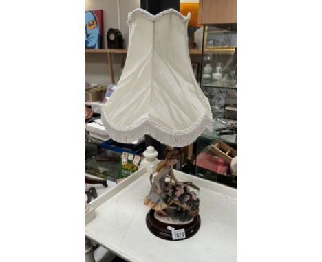 A table lamp with girl figure with a wheelbarrow of flowers