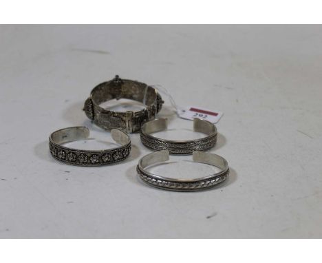 An early 20th century Eastern white metal hinged bangle, having engraved decoration and embossed with camels; together with t