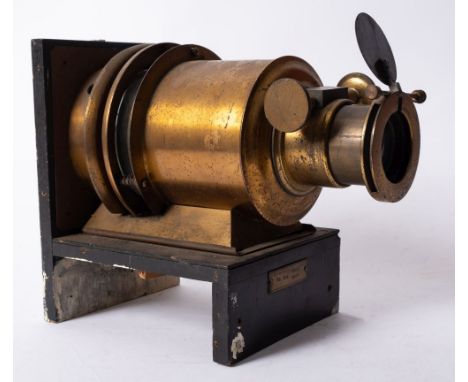 A lacquered brass 6 inch Magic Lantern lens on and ebonised base, 27cm long