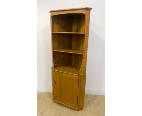 An Ercol elm corner unit, with three open shelves above a panelled cupboard door, standing on a plinth base, 180cm x 76cm x 4