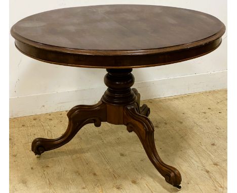 A Victorian mahogany tilt top breakfast table, with a circular top on a turned column and tripod base with porcelain casters,