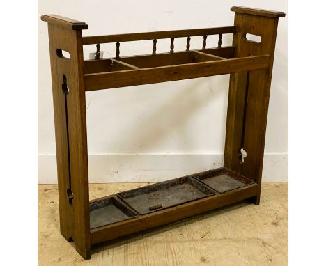 An Arts and Crafts oak stick stand, with a galleried back and carved side panels with pierced handles, with three open divisi