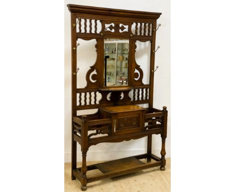 An Edwardian oak hallstand, with a carved and pierced frieze above a central rectangular bevelled plate with carved side pane