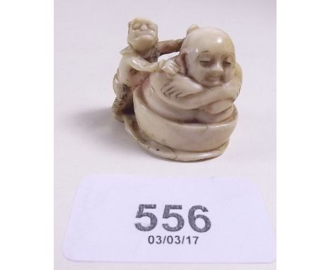 A Japanese Meiji period ivory netsuke carved seated old man in a wash tub with boy scrubbing his back, signed to base