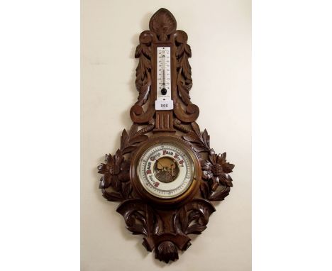 A continental oak carved barometer decorated foliage and flowers