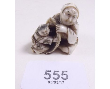 A Japanese Meiji period ivory netsuke carved seated woman with child in a basket, signed to base