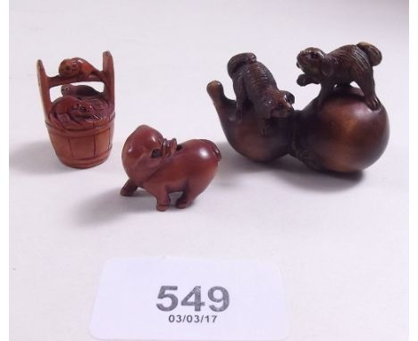 A Japanese carved netsuke of dogs and two smaller netsuke 