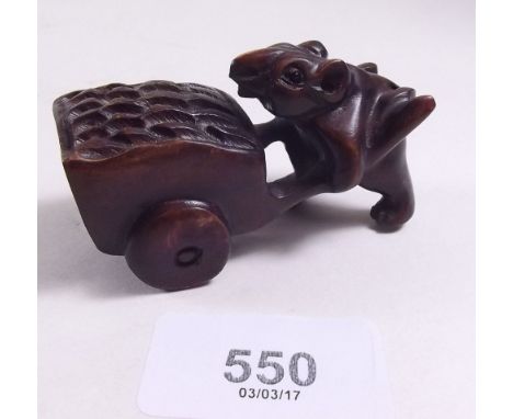 A carved and signed netsuke depicting a rat pushing a barrow 