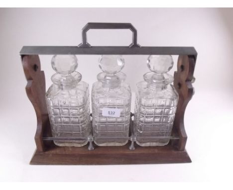 A three bottle oak tantalus - one decanter cracked