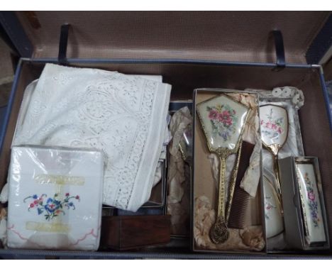 A vintage suitcase containing a quantity of vintage linen, dressing table sets, plated bowl, wooden trinket box and similar.