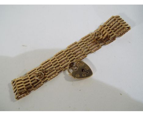 A hallmarked 9 carat gold gate bracelet with safety chain and locket, approximate weight 9.11 grams. Estimate £80 - £120