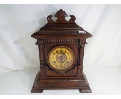 A good walnut cased American mantel clock, the case with carved an incised decoration, gilded dial behind cast brass glazed b