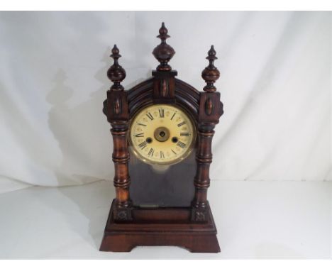 An early 20th century shelf clock, the case with glazed opening door, surmounted by three turned finial and flanked by bamboo