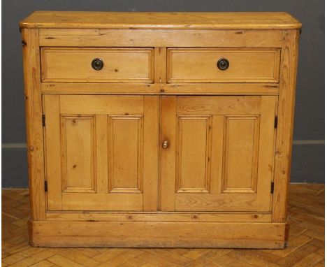 A pine kitchen cabinet having two drawers over a pair of panel doors, raised on a plinth base. W118cm