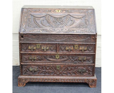 A George III carved oak bureau, the fall enclosing a fitted interior with well, over two short and two graduated long drawers