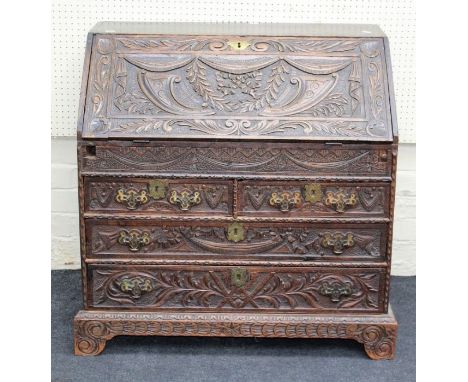 A George III carved oak bureau, the fall enclosing a fitted interior with well, over two short and two graduated long drawers