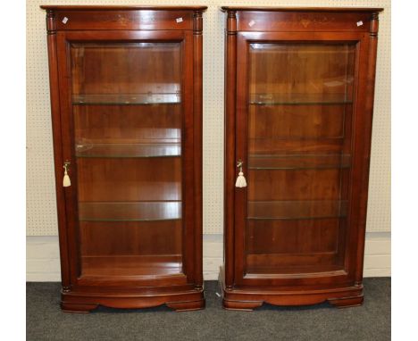 A pair of Continental hardwood narrow display cabinets having shallow bowfront glazed panel doors on plinth base, height 150c