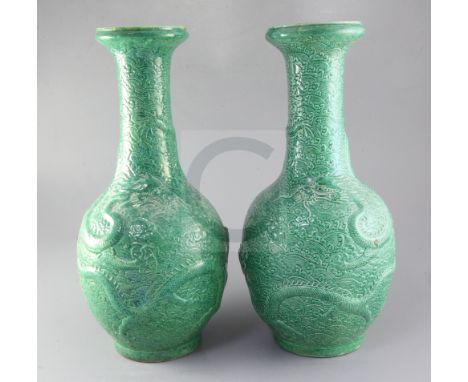 A pair of Chinese green glazed 'dragon' vases, late 19th/early 20th century, each moulded with dragons amid clouds, Kangxi ma